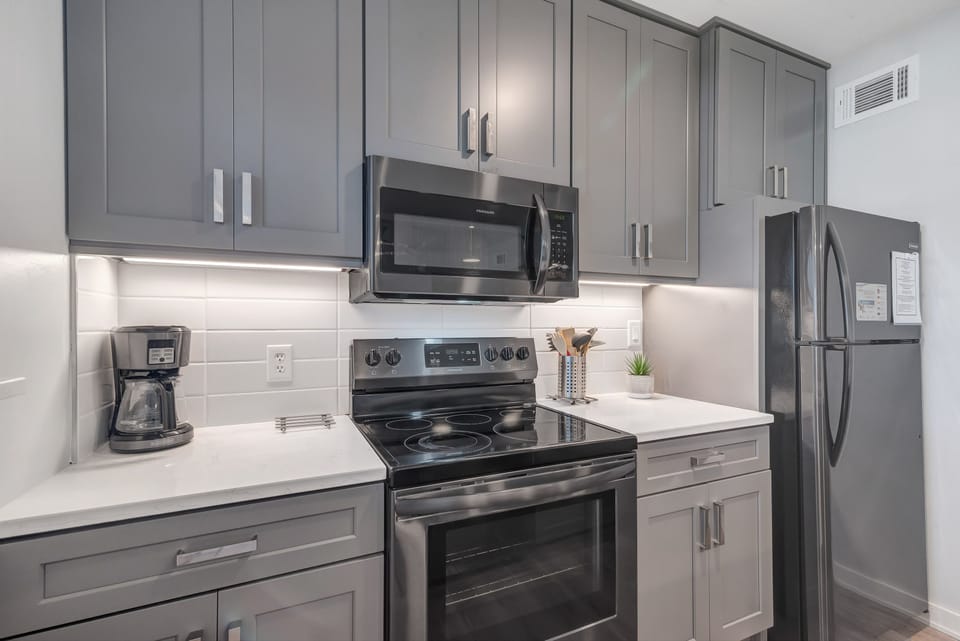 This fully functional kitchen boasts stainless steel appliances, sleek countertops, a decorative backsplash, and ample cabinet storage, ideal for everyday cooking and entertaining.
