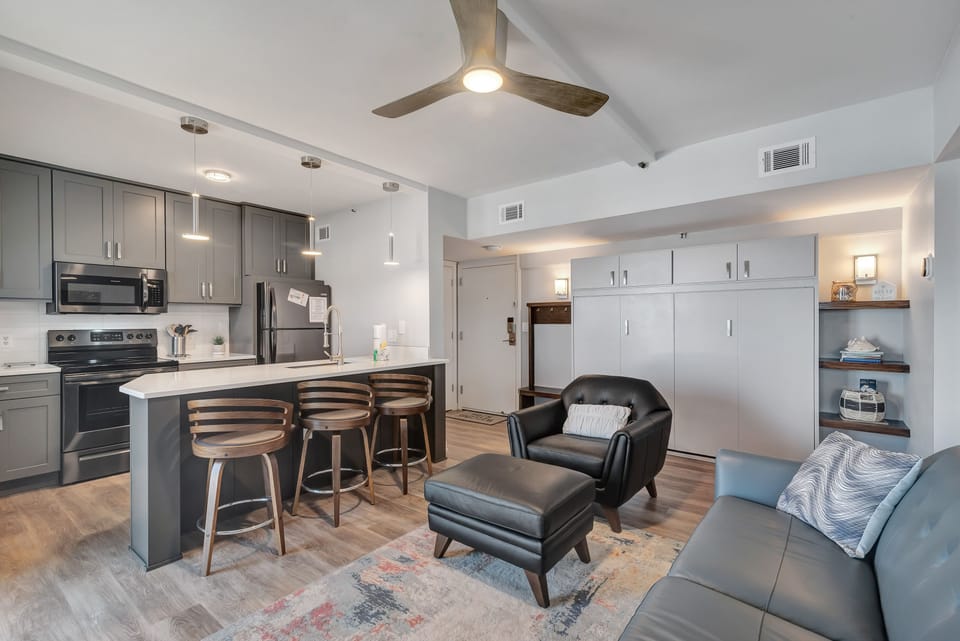 A comfortable living room with ample seating, flowing into the kitchen area, ideal for everyday living and gatherings.