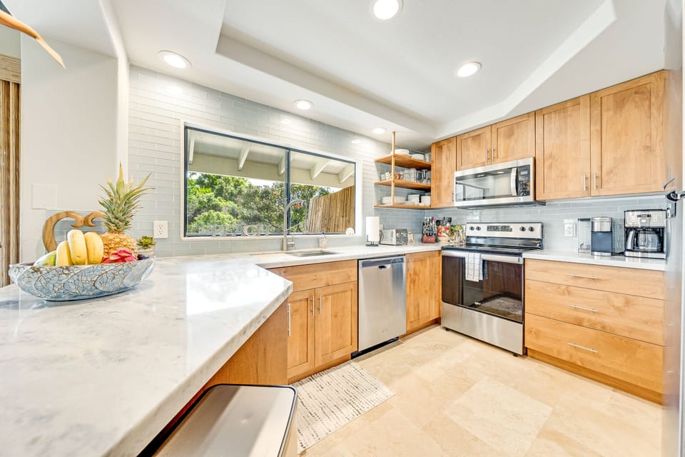 Full kitchen, dining area, and private lanai surrounded by tropical greenery
