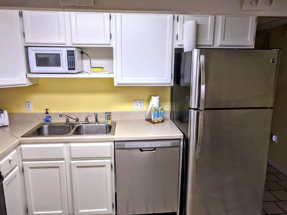 New stainless steel refrigerator, dishwasher, & small microwave above the sink.