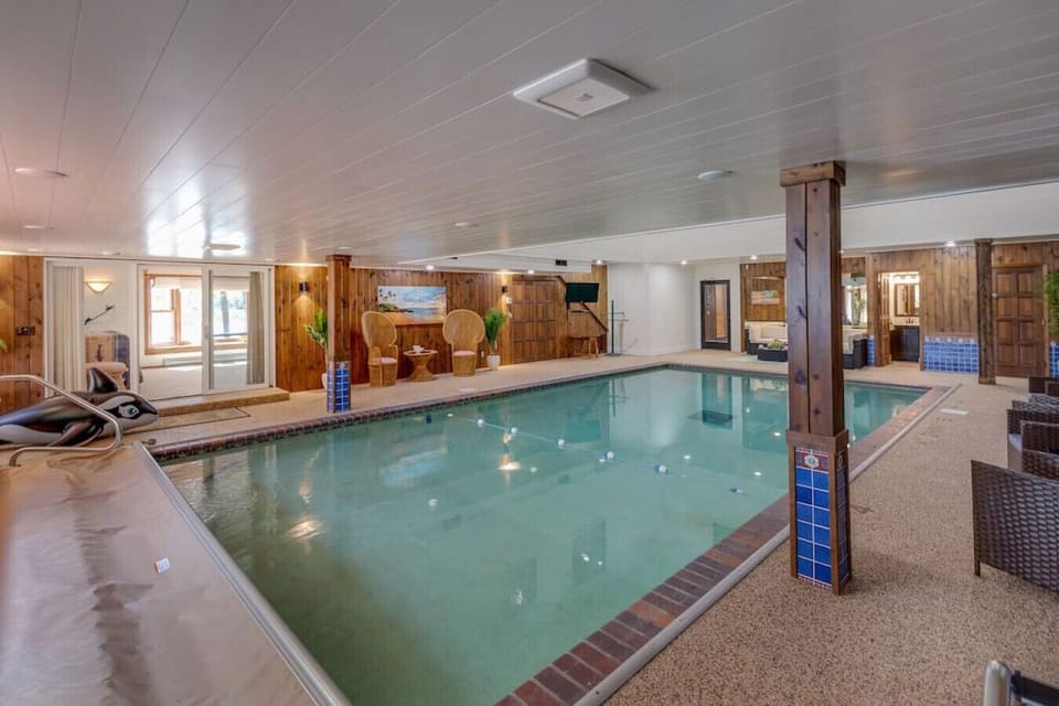 Private indoor swimming pool featuring large windows and recessed lighting.
