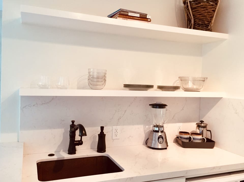 Quartz counters, copper sink, pull out faucet, floating shelves.