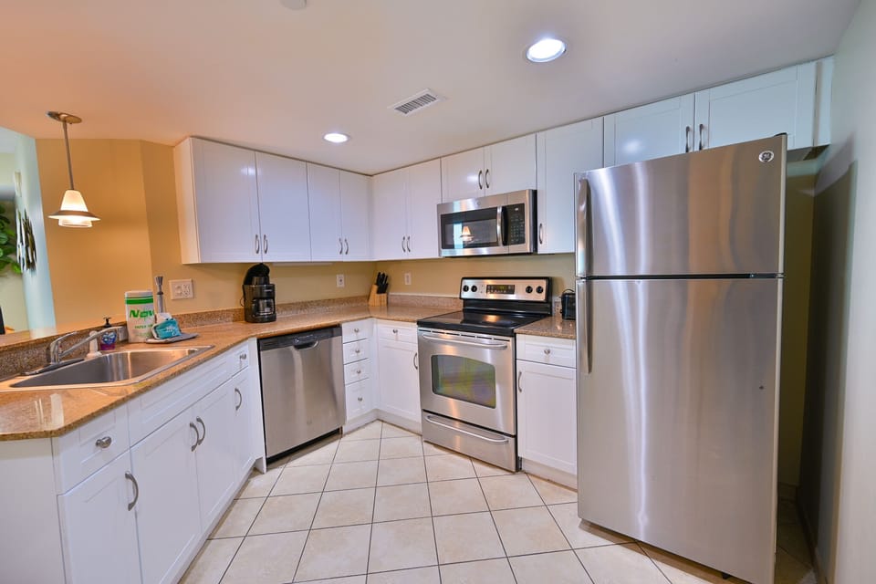 Bright modern kitchen with white cabinets, stainless appliances, and ocean views