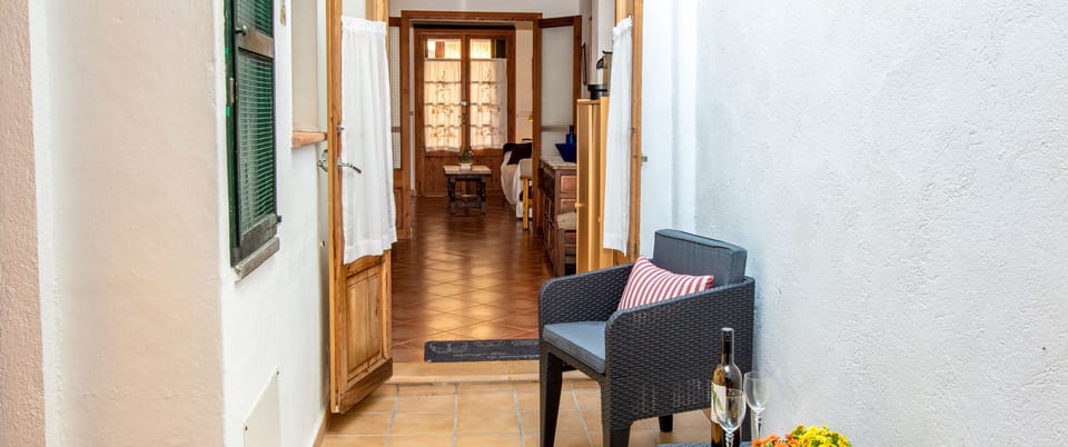 Small entrance terrace of a Mallorcan village house with an outdoor seating area and direct access inside.