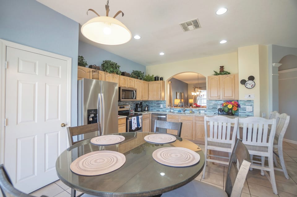 Kitchen table in nook that seats four.  Tile backsplash and undercabinet lights.