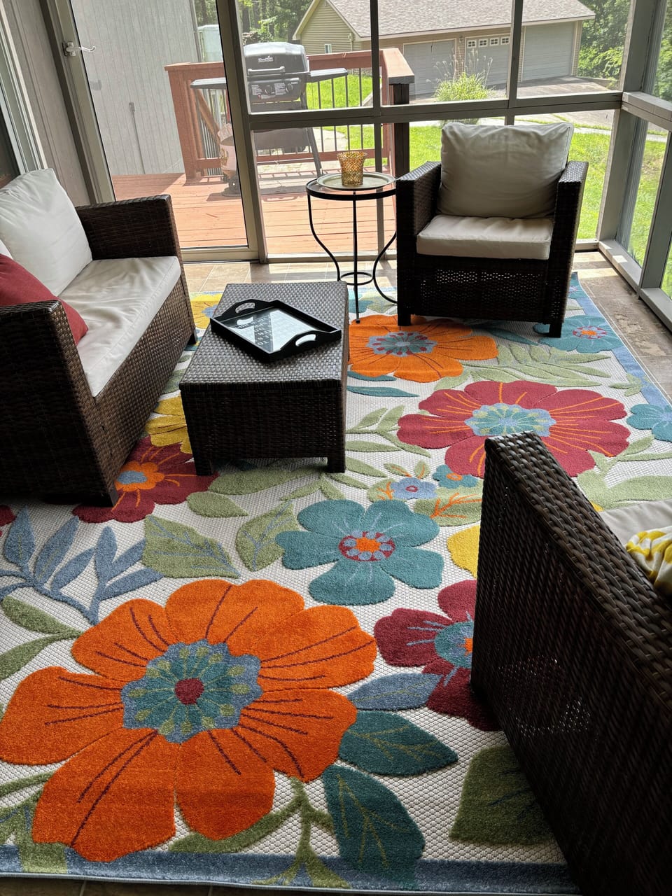 Screened-in porch leads to a red-wood deck with a grill. 