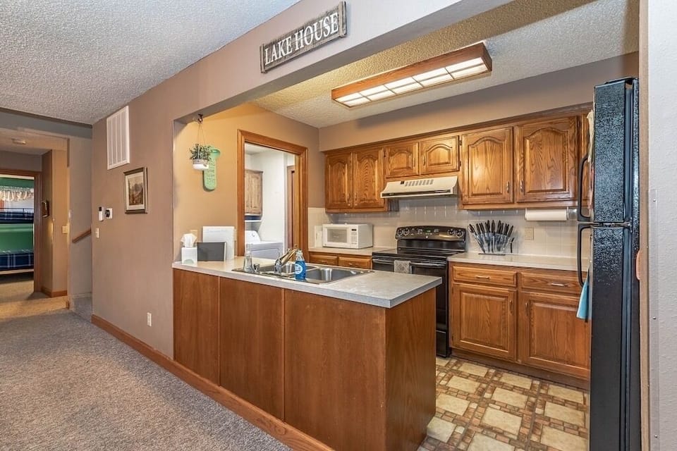 Kitchen with view into back room with washer/dryer and second fridge/freezer