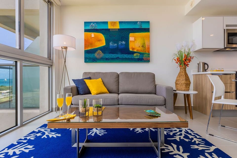 Bright and airy living space with vibrant art, comfy seating, and direct views to the sea—your perfect spot to unwind with morning juice or evening cocktails.