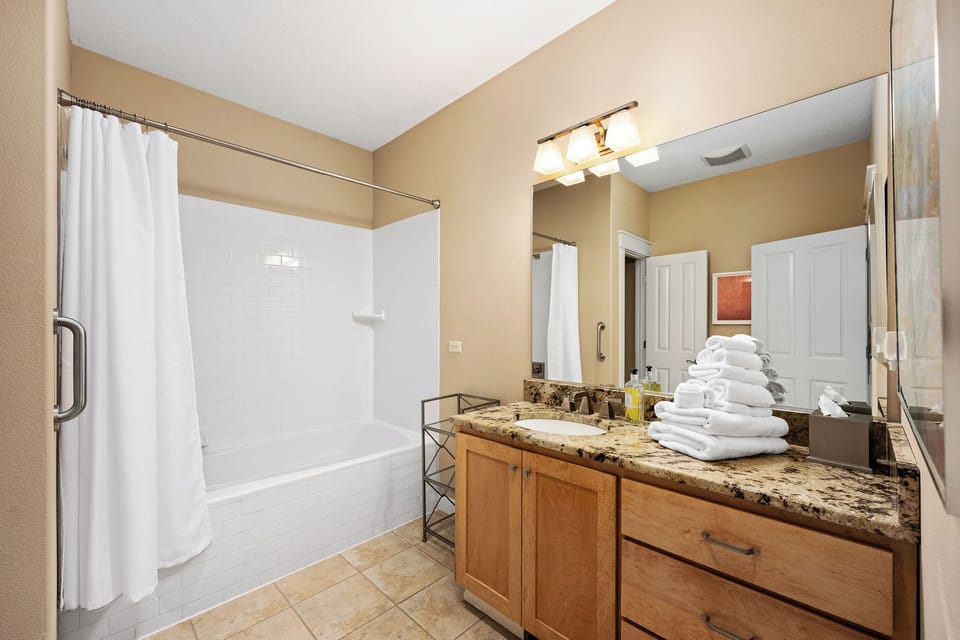 Step into your private bathroom sanctuary with granite counters, fresh towels, and a relaxing tub-shower combo.