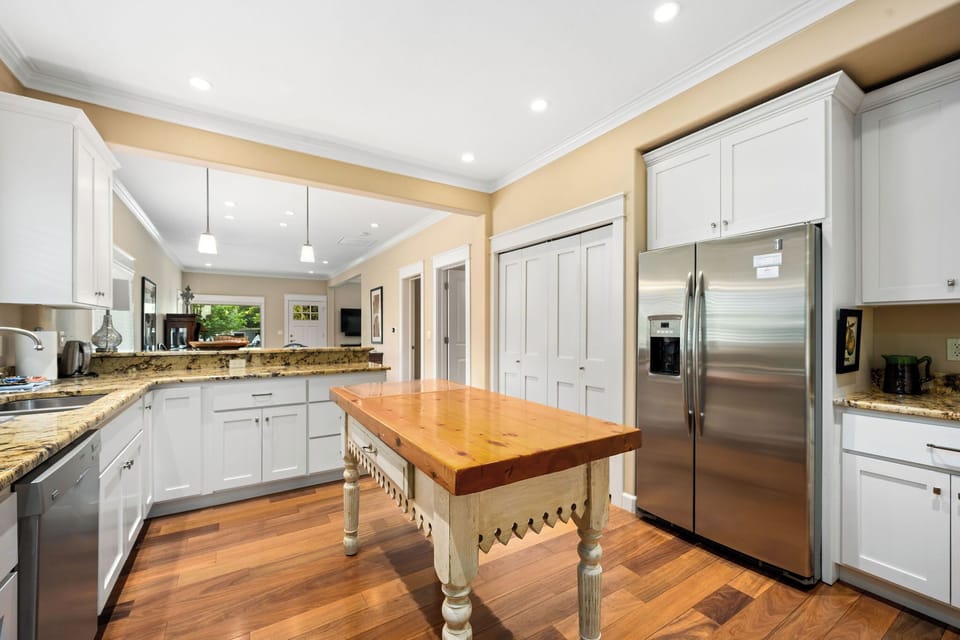 Your gourmet kitchen features elegant white cabinetry, granite countertops, and a charming farmhouse island perfect for cooking memorable meals.