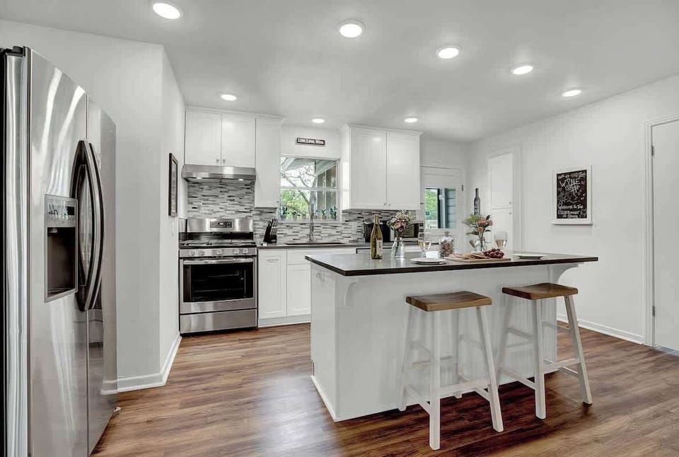 The kitchen features sleek stainless steel appliances and a compact island, complete with two chic barstools for a cozy breakfast