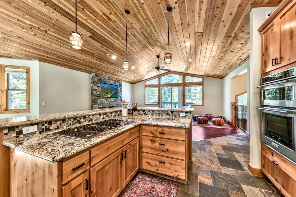 Cook in your gourmet kitchen with granite counters, rustic wood cabinets, and stunning mountain views through oversized windows.