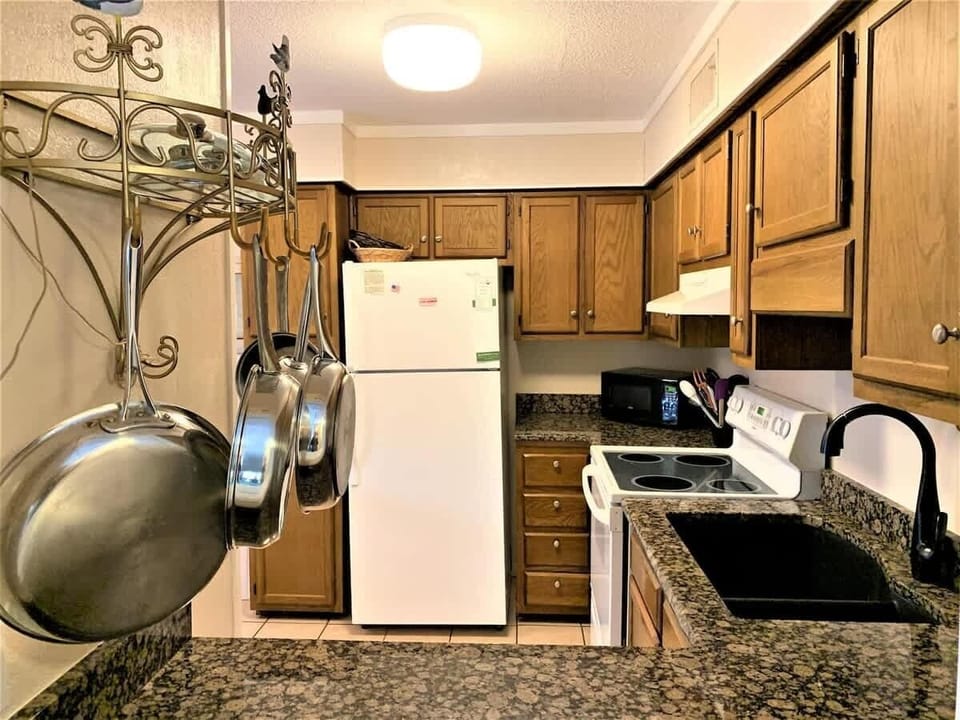 A fully equipped kitchen with classic wood cabinetry and white appliances.
