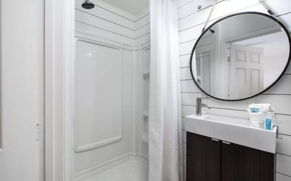 Step into your private spa-like retreat with modern fixtures, a spacious shower, and coastal shiplap walls that create the perfect sanctuary for unwinding.