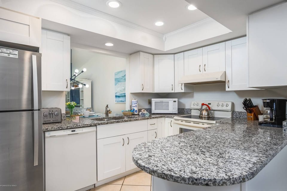 Updated and modern kitchen with white cabinets and solid stone black/white counter tops.