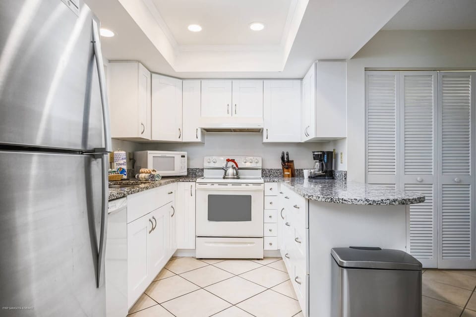 Stainless & white kitchen with solid stone counter tops, stocked with cookware.  Plenty of storage for all your favorite foods!