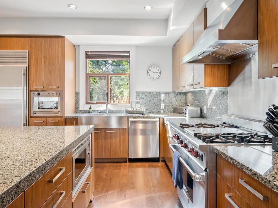 Gourmet professional kitchen with top-of-the-line stainless steel appliances, a built-in espresso machine and large island seating.