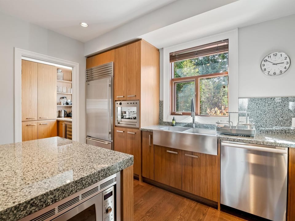 Gourmet professional kitchen with top-of-the-line stainless steel appliances, a built-in espresso machine and large island seating.