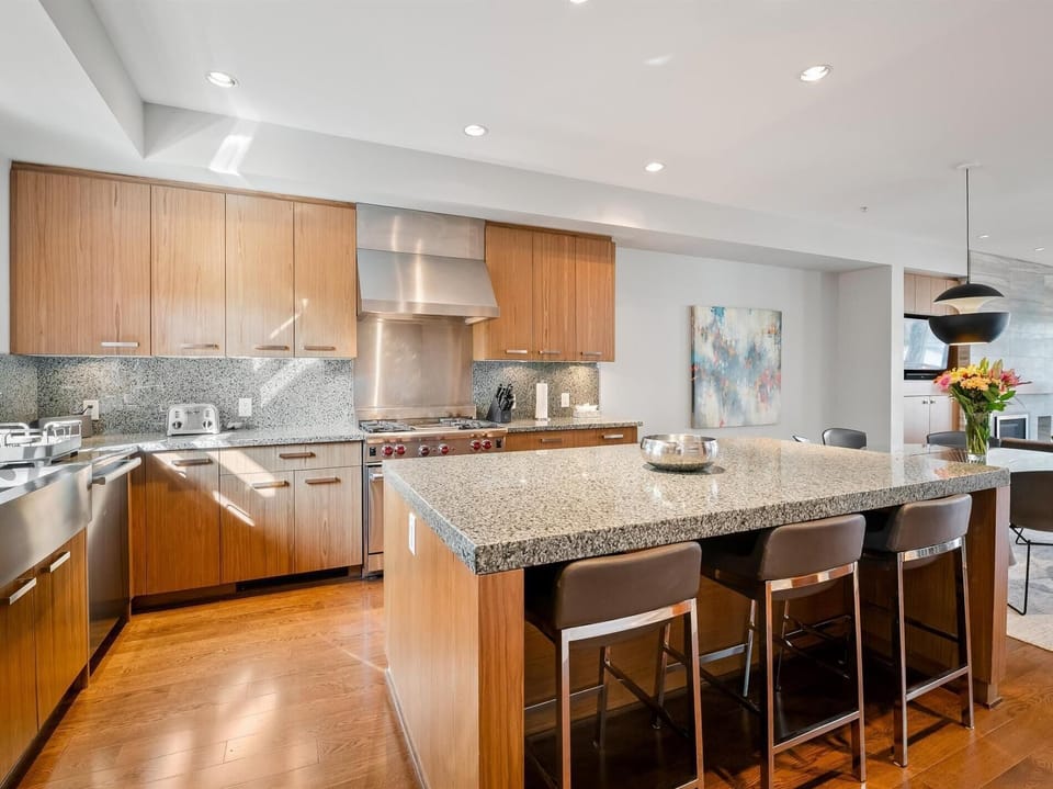 Gourmet professional kitchen with top-of-the-line stainless steel appliances, a built-in espresso machine and large island seating.