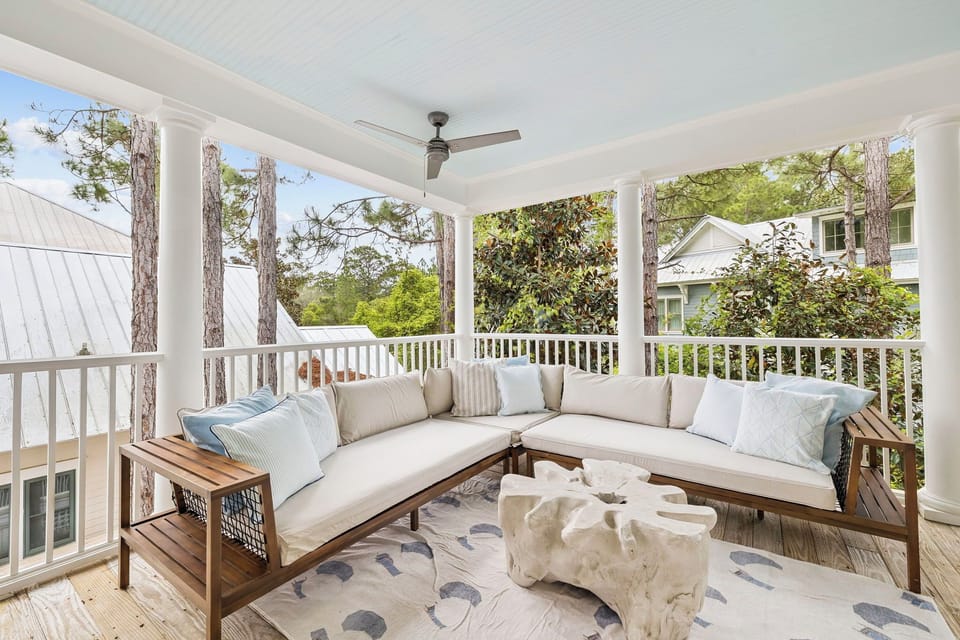 Unwind on your private covered porch with plush sectional seating and peaceful tree views through white railings.