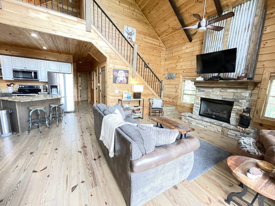 Cozy and inviting living room with floor to ceiling windows and fireplace. 