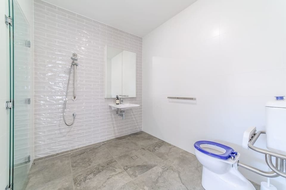 Accessible bathroom includes a folding frameless shower screen.