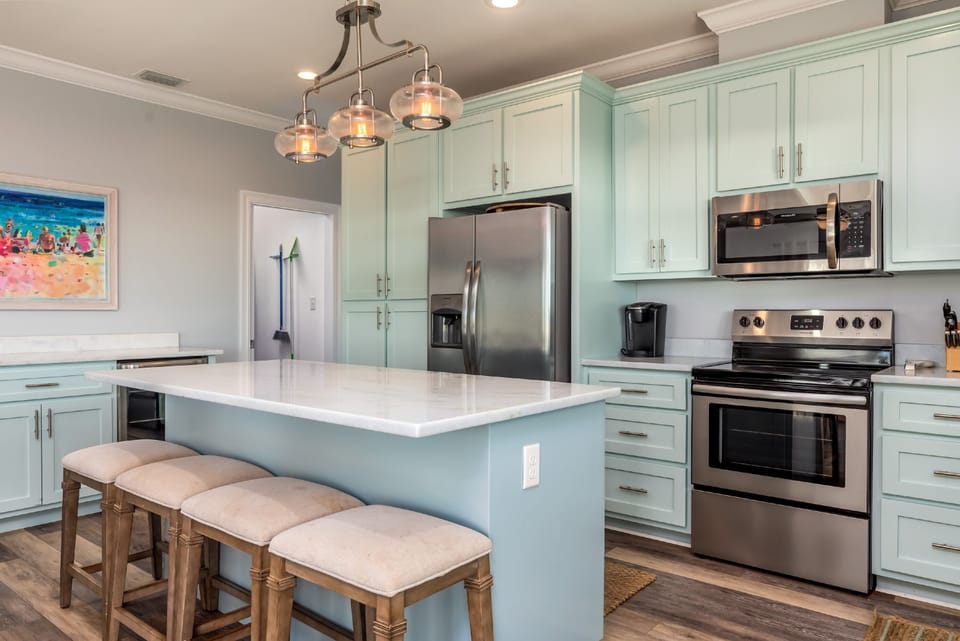 Fully equipped kitchen with stainless steel appliances, spacious island, and bar seating. Perfect for preparing fresh seafood dinners in your Dauphin Island beach house.