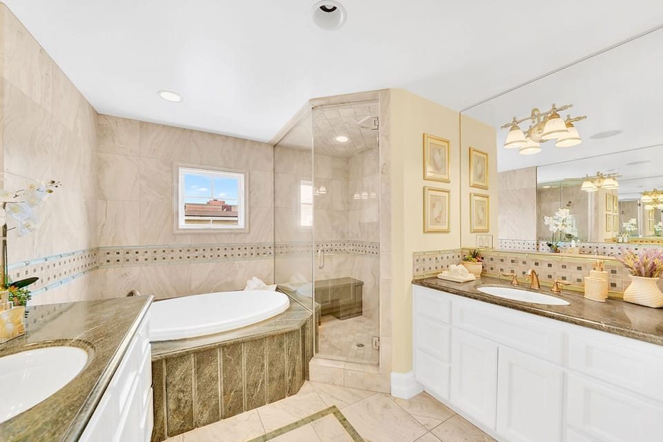 Primary bedroom's bathroom includes a large tub, walk-in shower, and two separate sink areas.
                