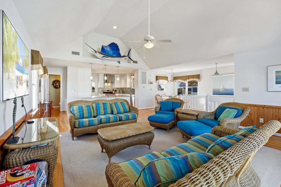 The top-level living area features high ceilings, abundant natural light, and comfortable seating for the whole family.