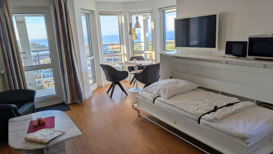 Compact living space with fold-down bed and sea view - living room