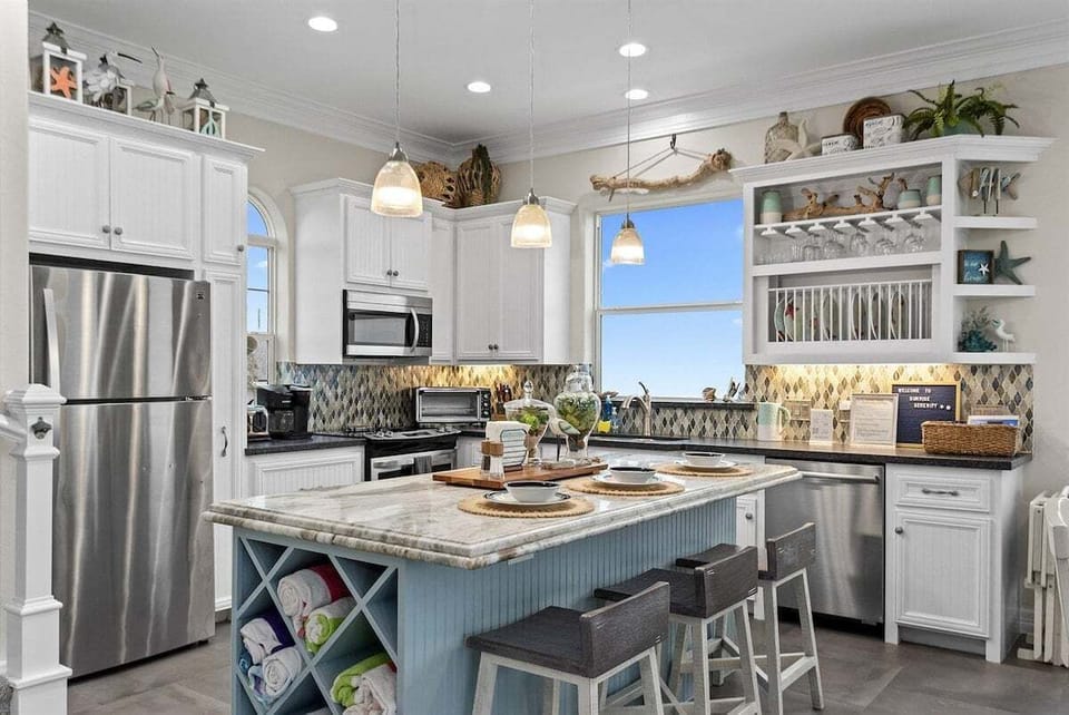 Fully equipped coastal kitchen with modern appliances, island seating, and open layout.
