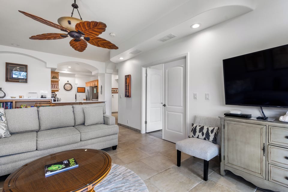 Sink into comfort in your open-plan living room, complete with coastal-inspired décor, a tropical ceiling fan, and a flat-screen TV for relaxing evenings.