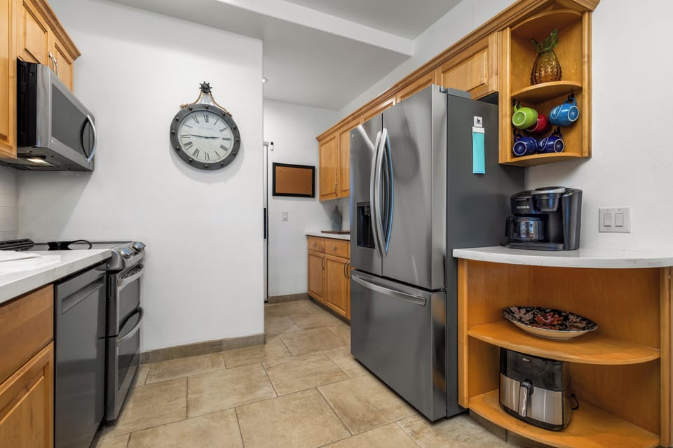 A fully equipped kitchen with stainless steel appliances, warm wood cabinetry, and a coffee maker ready for your morning brew, complete with everything you need to prepare your favorite meals.