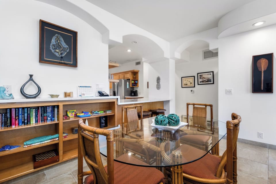 Gather around the glass-top dining table in this open, light-filled space. Arched ceilings flow naturally into the kitchen area, while tropical decor and colorful art create a warm, island-inspired retreat for your stay.