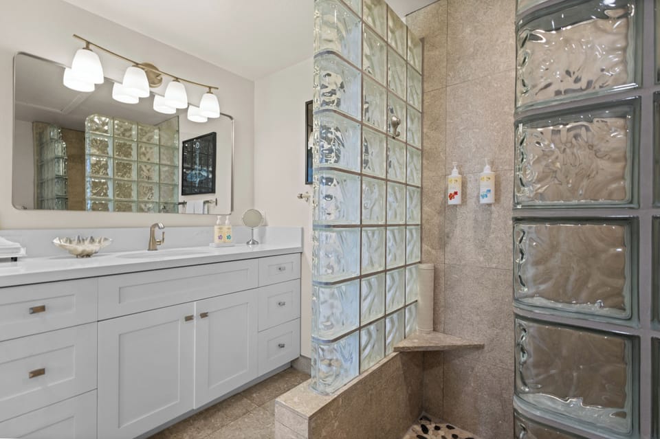 Refresh in your bright, spa-like bathroom featuring elegant glass block walls and ample vanity space, designed to make your morning routine a pleasure.