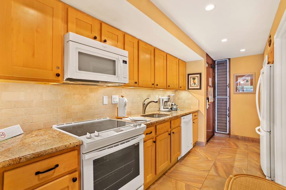 Cook your favorite meals in this well-equipped kitchen featuring warm wood cabinetry, granite counters, and full-size appliances ready for your culinary adventures.