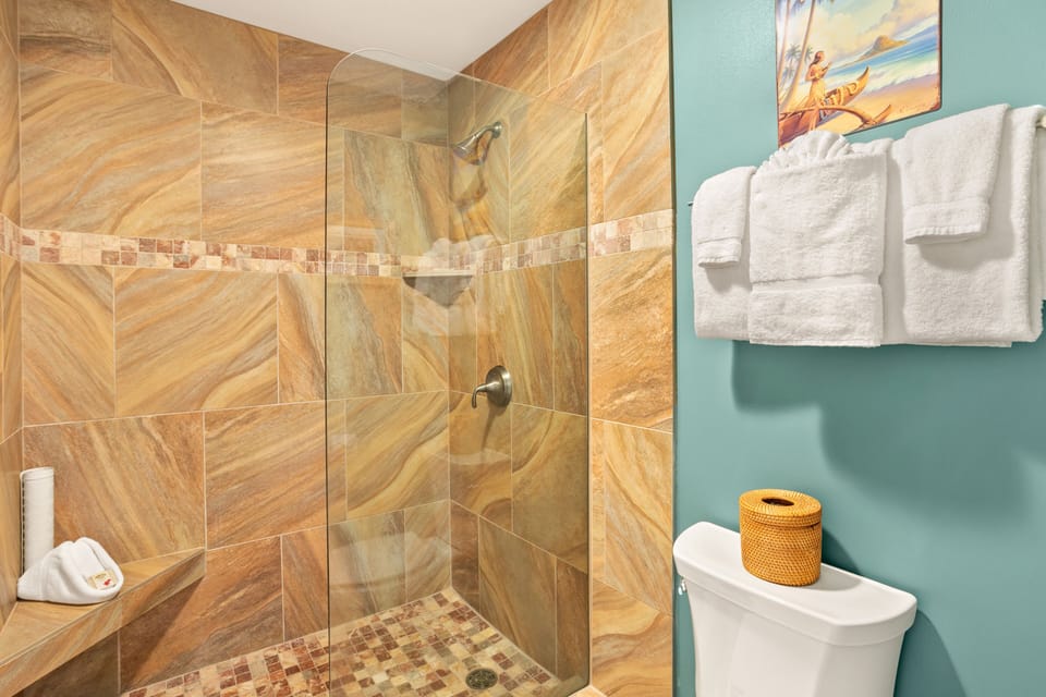 Freshen up in your sleek walk-in shower with elegant stone tiling and glass enclosure. Fluffy towels and cheerful décor create a welcoming, spa-like retreat.