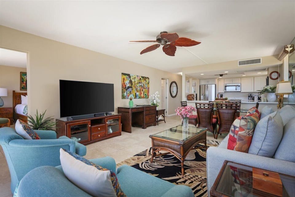 Your coastal retreat features an open-plan living space where vibrant turquoise seating invites relaxation under tropical ceiling fans, perfect for unwinding after beach days.