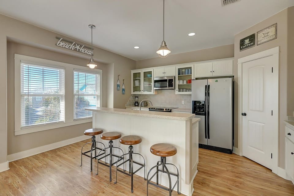 Your bright coastal kitchen features modern appliances and a breakfast bar perfect for morning coffee or casual meals together.