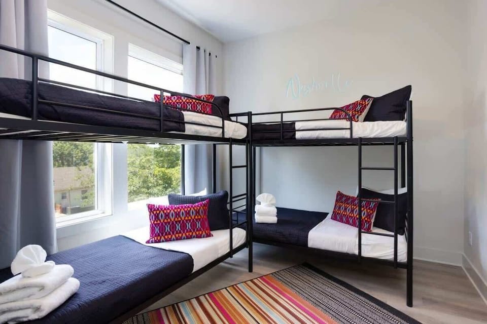 A Nashville sign on the wall sets the vibe in this bunk bedroom with windows that let the light in, perfect for the crew that wants to keep the energy going