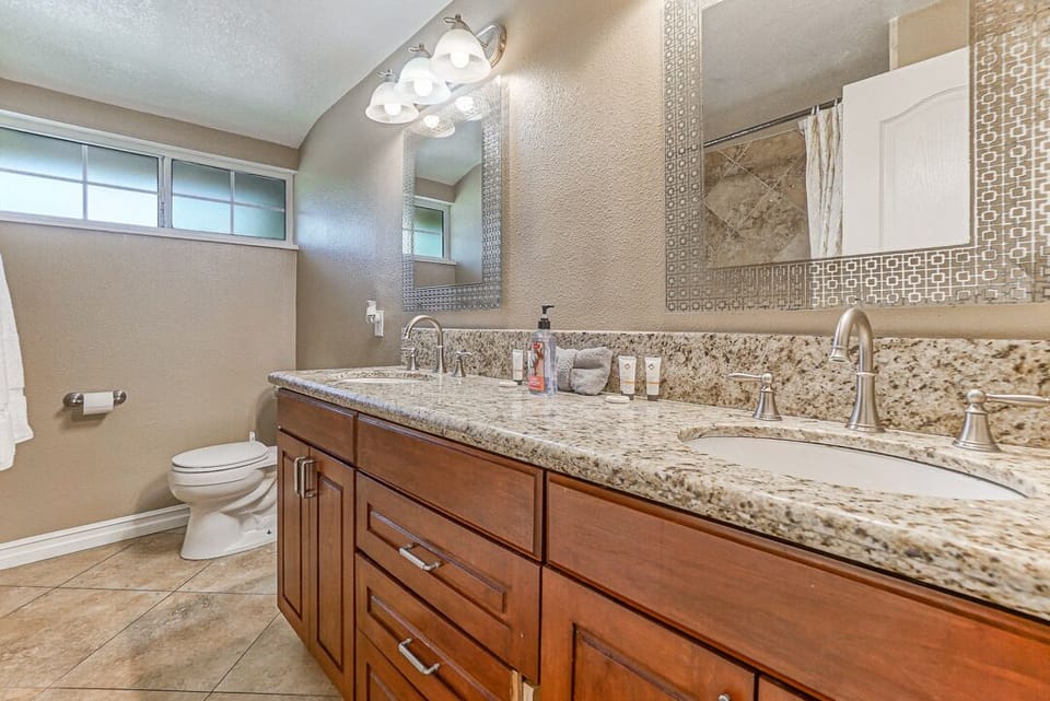 - Bathroom with granite dual sinks and wood cabinetry style   - Bright lighting and mirrors provide a refreshing setup   - Functional space perfect for getting ready each morning