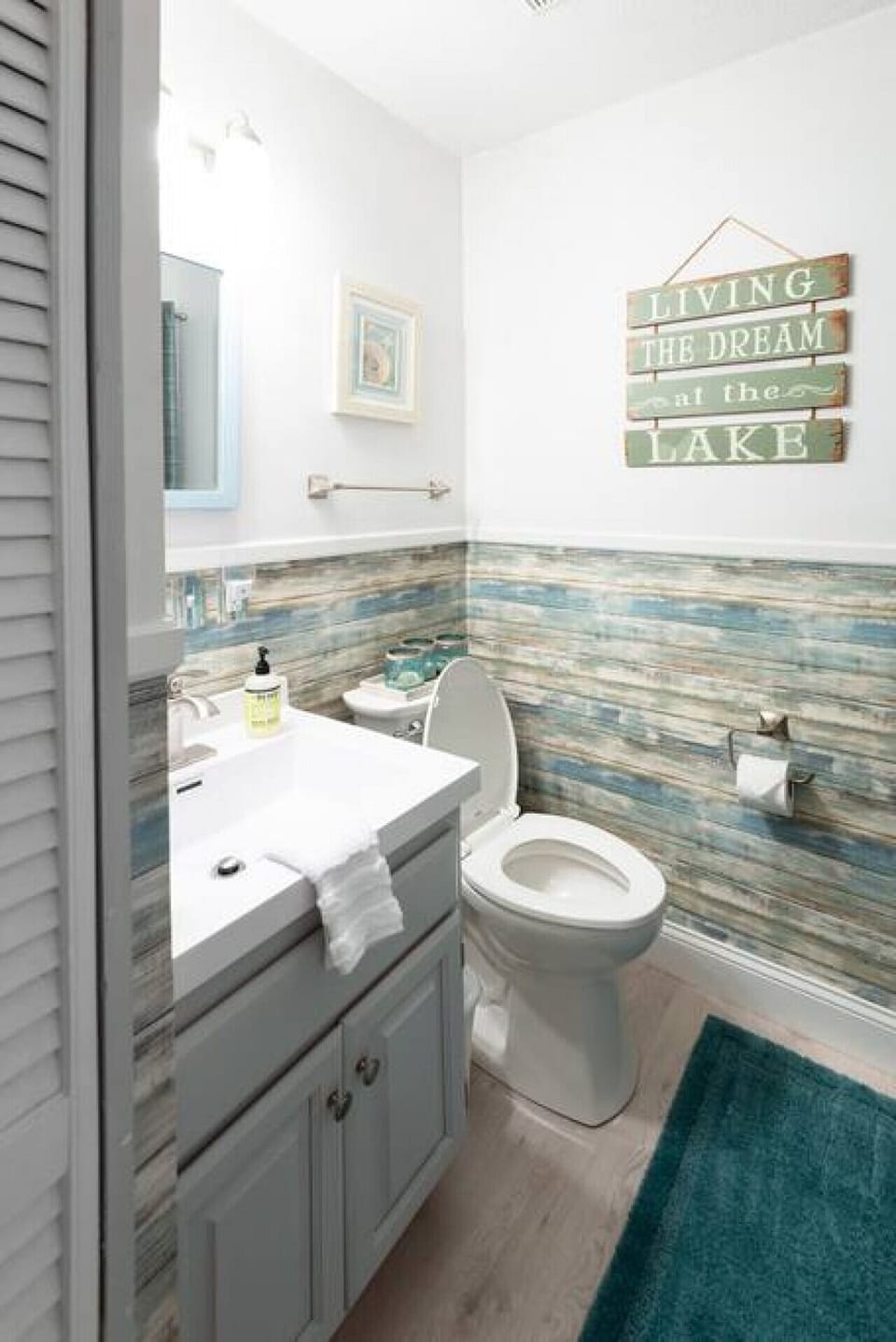 The second bathroom provides a white vanity, toilet, generous counter space, and lake-themed finishes.