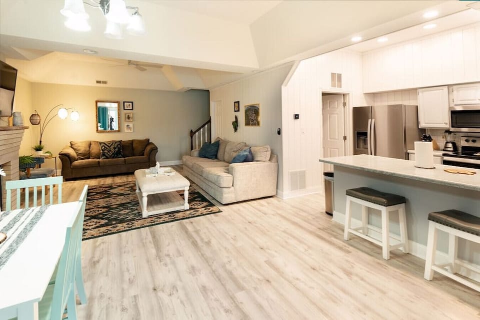 The opposite Condo 2 angle documents the kitchen island, lounge seating, television, staircase, and open circulation.