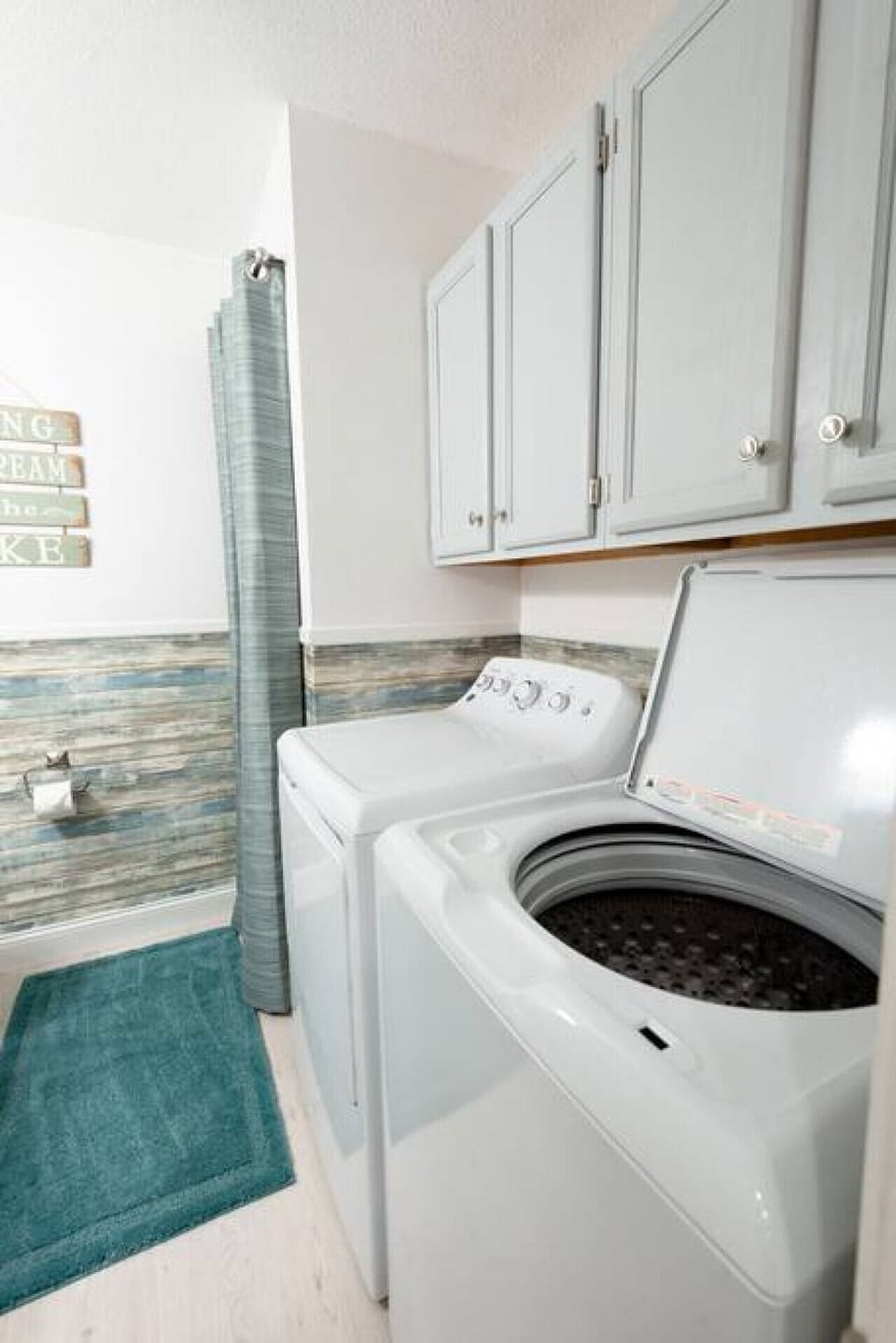 Condo 1 includes a dedicated laundry room with full-size washer, dryer, upper cabinetry, and storage space.