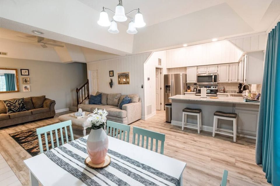 A wide angle shows Condo 2's dining space, breakfast bar, full kitchen, and lounge arranged for easy group time.