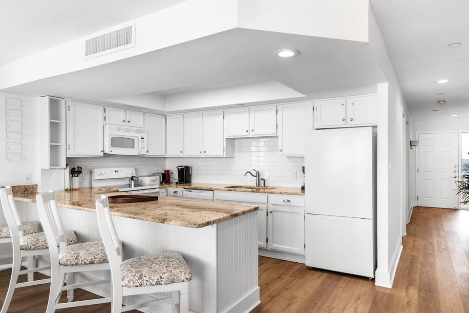 Your fully equipped kitchen features granite countertops and breakfast bar seating, perfect for morning coffee or preparing meals together.
