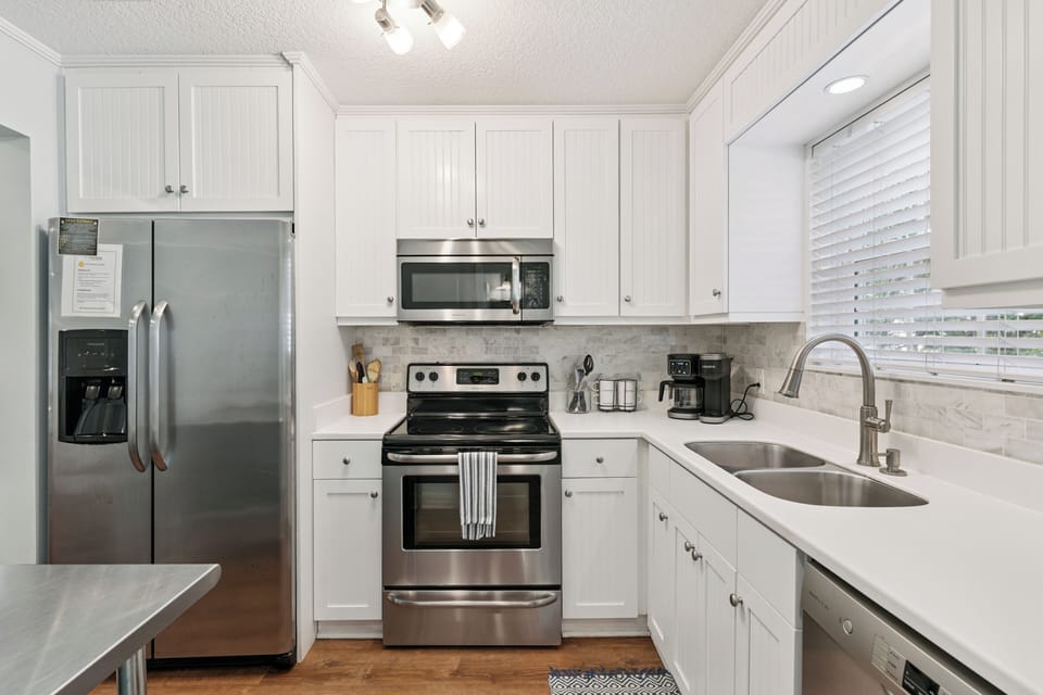 Your fully-equipped kitchen features stainless steel appliances, bright white cabinetry, and ample counter space—perfect for preparing meals during your stay.
