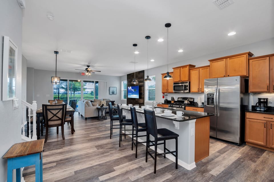 Modern kitchen of the townhouse in Davenport Florida - Sleek stainless steel appliances - Well-lit workspace with strategically placed task lighting - Breakfast bar with high chairs - Smart use of space with versatile storage solutions