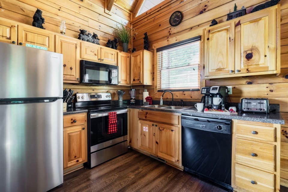 Boasts wooden cabinets, stainless steel appliances, a black dishwasher.