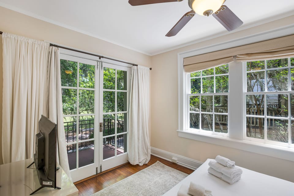 Step over to the cheerful bedroom, that features a plush queen size bed, balcony, dresser, and smart television.